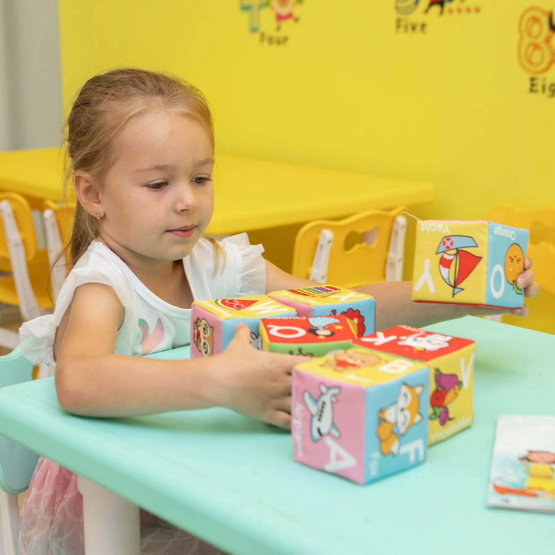 Девочка собирает слова из кубиков на занятии в Kiddie English